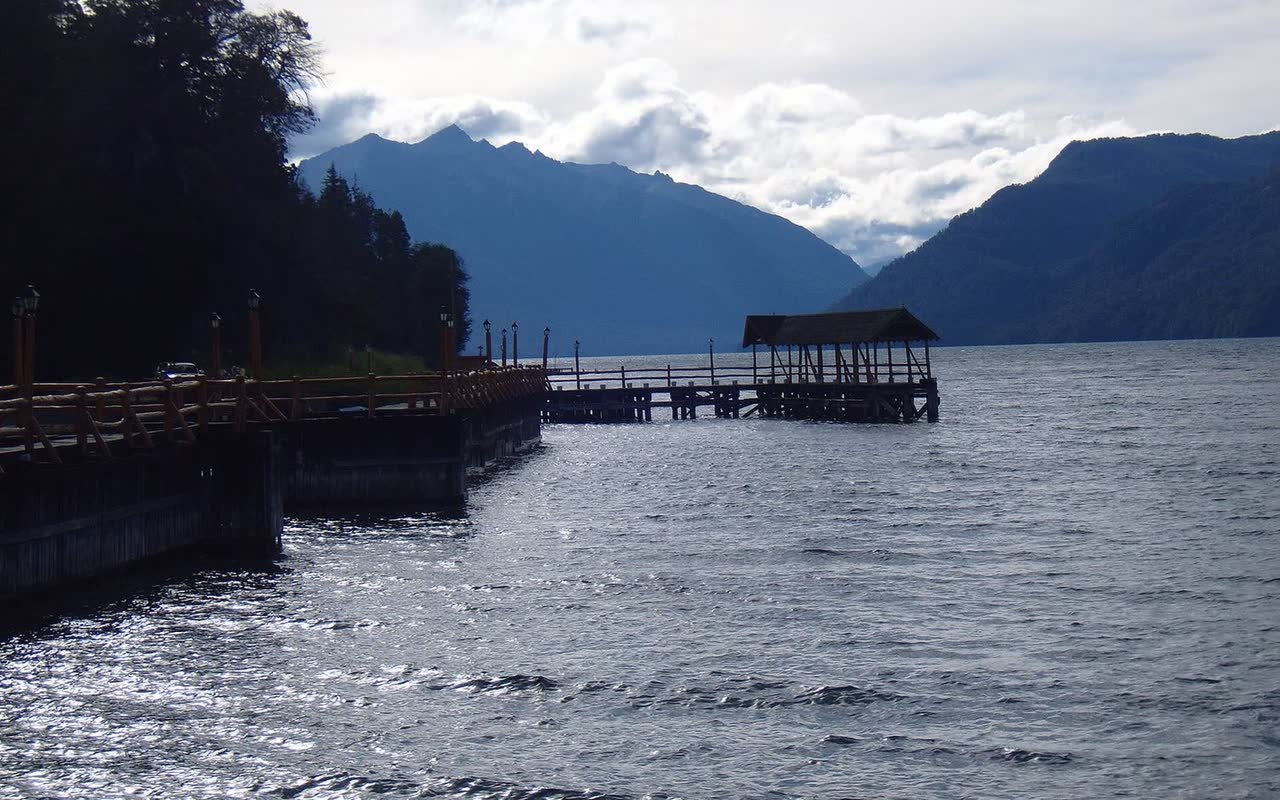 Muelle de madera sobre el lago con la cordillera de fondo